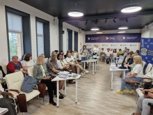 Групове фото учасників та учасниць конгресу, що слухають виступ спікера у конференц-залі.