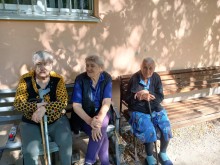Три жінки похилого віку сидять на лавці біля Будинку ветеранів в Умані
