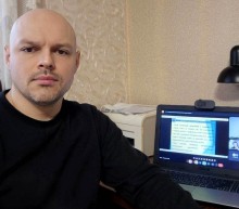 Представник військової адміністрації сидить за столом та слухає доповідача на семінарі