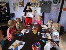 Діти сидять за столом, фахівець Центру розповідає про державні символи та орнаменти, демонструючи зображення