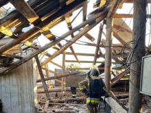 Рятувальники стоять на даху та дивляться на зруйновану ворогом покрівлю