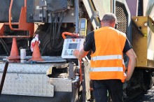 Робітник працює з технікою, яка ремонтує дорожне покриття