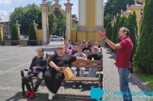 Покровські школярі сидять на лавках та уважно слухають екскурсовода, який розвідає про історичні пам'ятки.