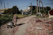 Жінка тягне воду на фону розбитих будівель