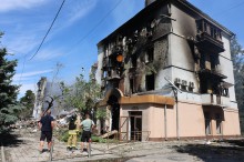 Люди стоять біля зруйнованого та обгорілого будинку в Краматорську