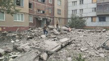 Зруйнований будинок після ворожого обстрілу та люди, які ходять біля руїн