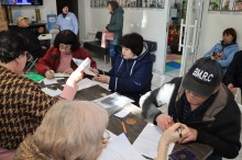 Відвідувачі Центр підтримки ВПО «СЕЛИДОВЕ.UA», заповнюють документи.