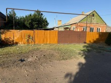 Воронка від ворожого обстрілу біля паркану та подвір'я в приватному секторі.