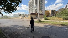 Правоохоронець стоїть біля багатоповерхової будівлі, пошкодженої ударом