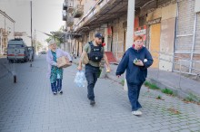 Жінки несуть гуманітарну допомогу, їм допомагає волонтер