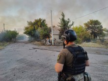 Правоооронець стоїть на фоні палаючої будівлі після ворожого обстрілу.