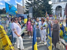 Жінки та чоловіки з квітами ідуть по алеї Слави у місті Київ.