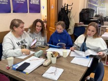 Діалогова зустріч жінок. Жінки сидять за столом, обговорюють питання, спілкуються.