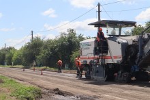 Ремонтники за допомогою будівельної техніки лагодять дорожнє покриття.
