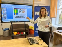 Учасниця зустрічі стоїть біля лед-екрану в руках тримає білий папір, позаду неї банер логотипом  Smarta громадської організації Смарта
«МиРазом» Центр підтримки ВПО Краматорського району