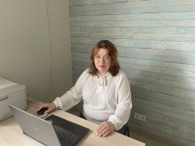 Директорка ГО «Простір позитивних змін» Наталії Стаднічук у білій сорочці біля ноутбука