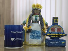 Сувенірна продукція. Стела Донеччини, лялька мотанка та синя кружка з написом про партнерство