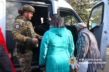 Дві літні жінки сідають до евакуаційного автомобіля, їм допомагає поліцейський