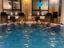 Спільне фото дітей у басейні. Посередині тренер. В басейні блакитна вода