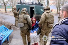 Поліцейські екіпажу "Білі янголи" несуть неходячу жінку до евакомобіля, їх напарник чатує небо від дронів