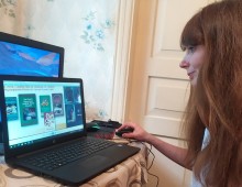 Представниця бібліотеки захоплено дивиться в екран монітора, на якому показують книжки про український фольклор та обряди.