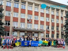 Спільне фото. Представники громад стоять біля фасаду адміністративного будинку, тримають прапори громад.