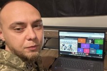 Капітан В’ячеслав Буліч у військовій формі біля ноутбука з відкритою відеоконференцією