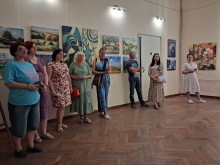 Група відвідувачів стоїть у виставковій залі та розглядає картини на стінах