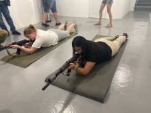 Дві жінки на карематах вчаться цілитись з автоматичної зброї.