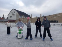 Ковзанка Хлопець тримається за  прилад для навчання їздити на ковзанах, діти на ковзанах машуть рукою