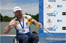 Учасник чемпіонату, посміхається та тримає соняшник у кріслі колісному на фоні банера чемпіонату.