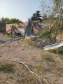 Зруйнований одноповерховий будинок та пошкоджені дерева через російські обстріли.