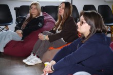 Представники громади сидять на пуфах та уважно слухають.