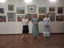 Спікери виступають перед аудиторією на тлі стіни з картинами в художній галереї