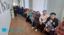 Учасники виставки сидять на стільцях та дивляться та уважно слухають.