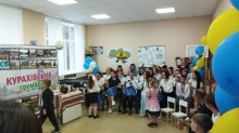 Урочистий захід: першокласники вітають майбутніх випускників, даруючи подарунки. На стіні банер «Курахівська громада».