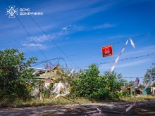 Вулиця. Територія огороджена колючим дротом, на якому висить табличка "Обережно міни".