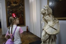 Дівчина уважно розглядає скульптуру.