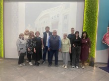 Автор книги Володимир Сутковий разом із гостями та учасниками презентації у VCENTRI HUB на фоні слайду з будівлею бахмутського театру
