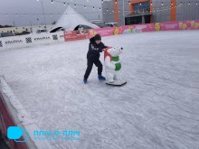 Хлопець стоїть на ковзанках та тримається за навчального ведмедя.