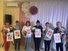 Учасниці майстер-класу позують зі своїми завершеними картинами та букетами квітів