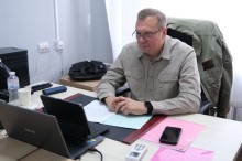 Олександр Шевченко сидить за робочим столом перед відкритим ноутбуком.