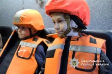 Двоє дітей в машині в бронежилетах та касках