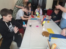 Діти з інвалідністю під час майстер-класу з виготовлення свічок із вощини. У руках – яскраві саморобні свічки та матеріали