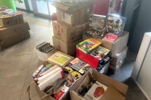 Картонні коробки та сумки, наповнені дитячими книжками та настільними іграми