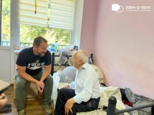 Заступник начальника Часовоярської громади Руслан Прийменко спілкується з чоловіком похилого віку. Чоловік сидить на ліжку, посміхається та спілкується.