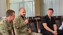 Заступник голови Донеччини Юрій Ключка та двоє чоловіків у військовій формі, сидять на стільцях. Один з них розповідає, інші уважно слухають.