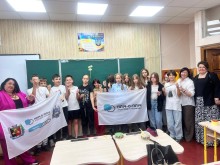 Спільне фото дітей. Діти разом з учителем стоять біля шкільної дошки та тримають прапори громад.