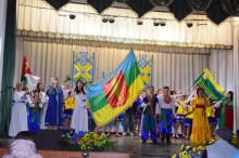 На сцені народний колектив у вишиванках, чоловіки тримають прапор громади.