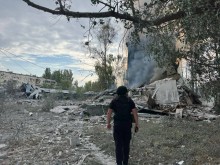 Правоохоронець стоїть біля зруйнованого окупантами багатоквартирного будинку